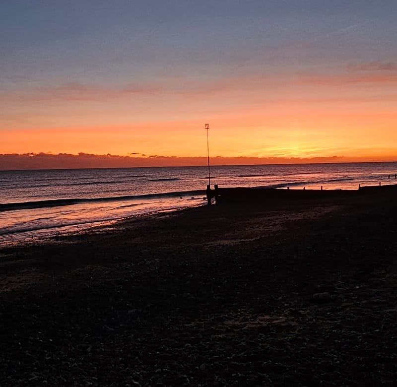 Dusk over the sea with a marker post at the water's edge