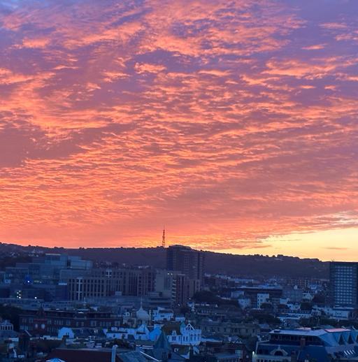 Pink and orange clouds over town rooftops